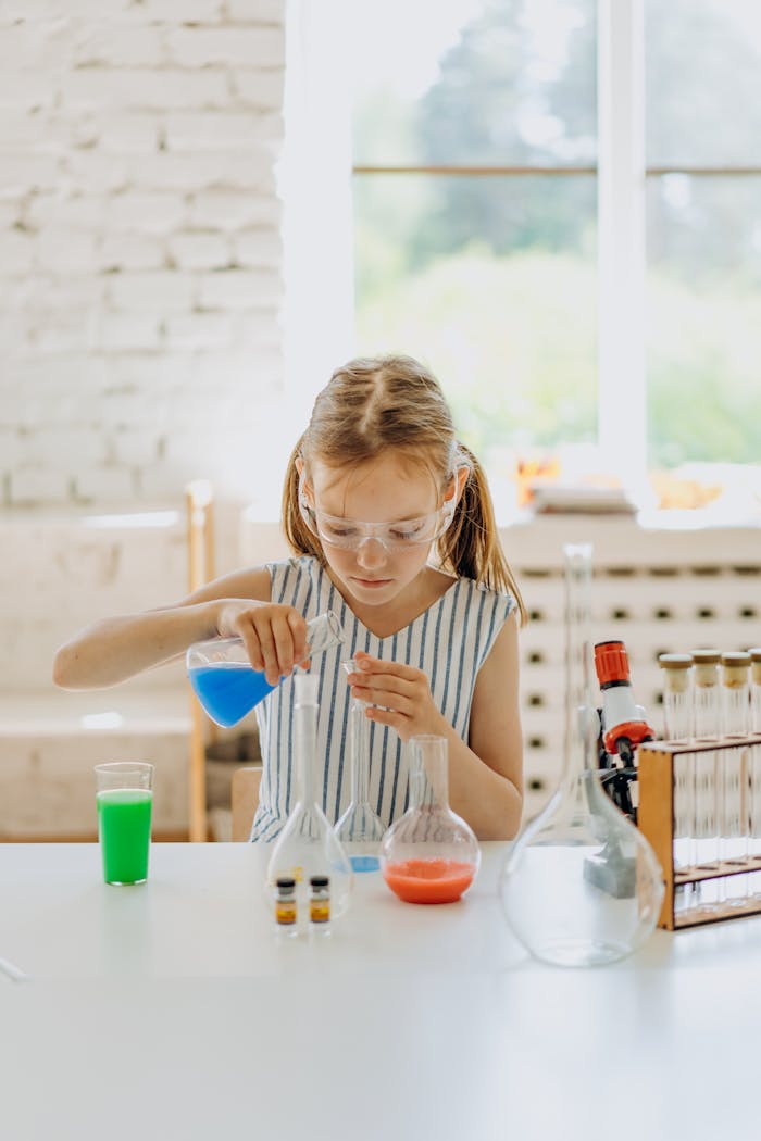 Young girl wearing goggles conducting a science experiment with colorful liquids at a home lab setup.